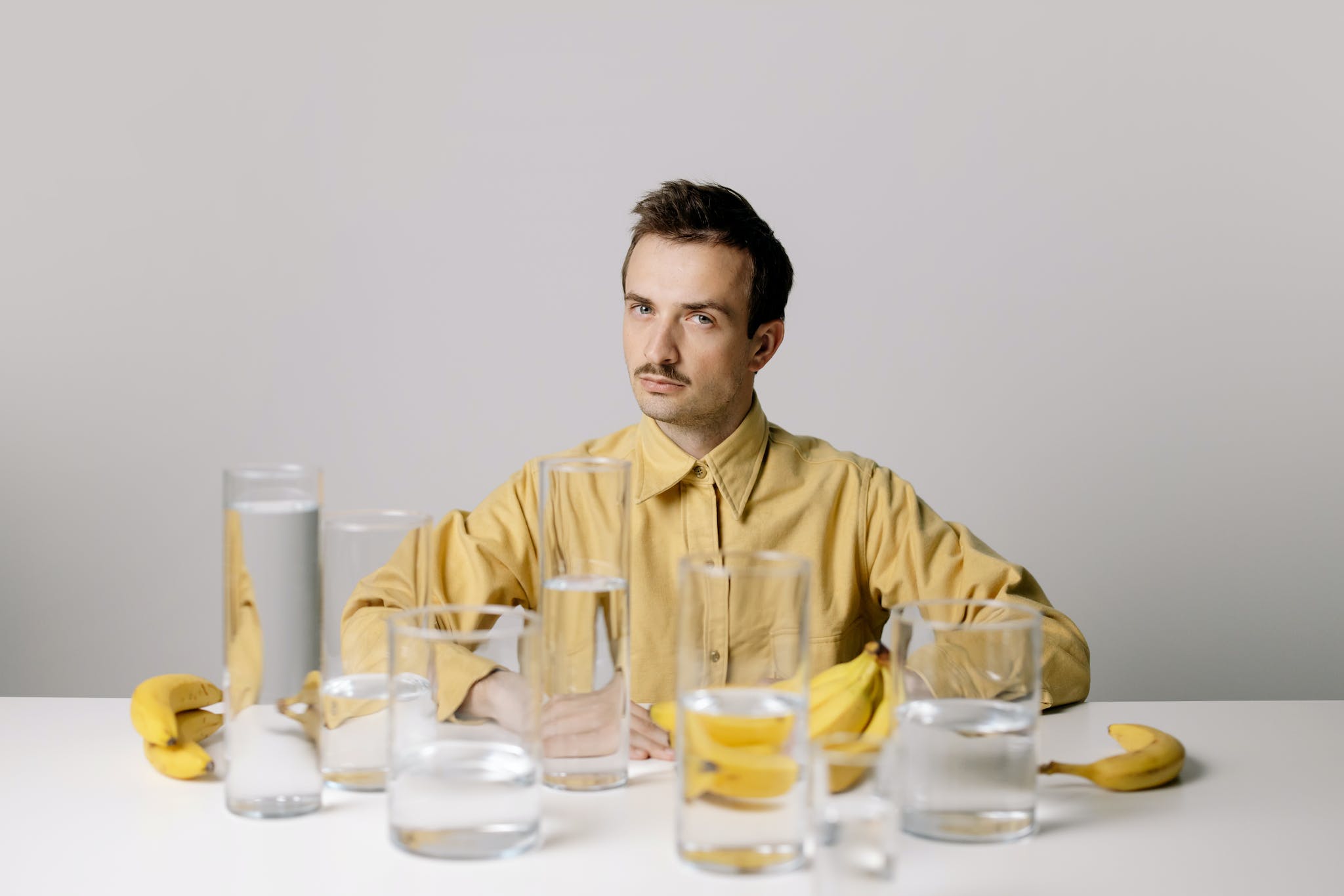 Man in Yellow Dress Shirt Sitting Beside Table With Drinking Glasses - banana tea